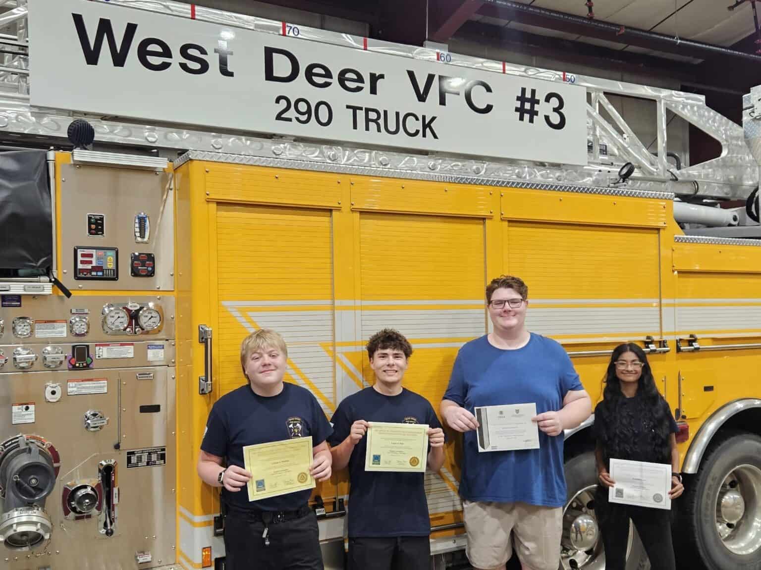 Four young people holding certificates stand in front of a yellow West Deer VFC #3 fire truck.