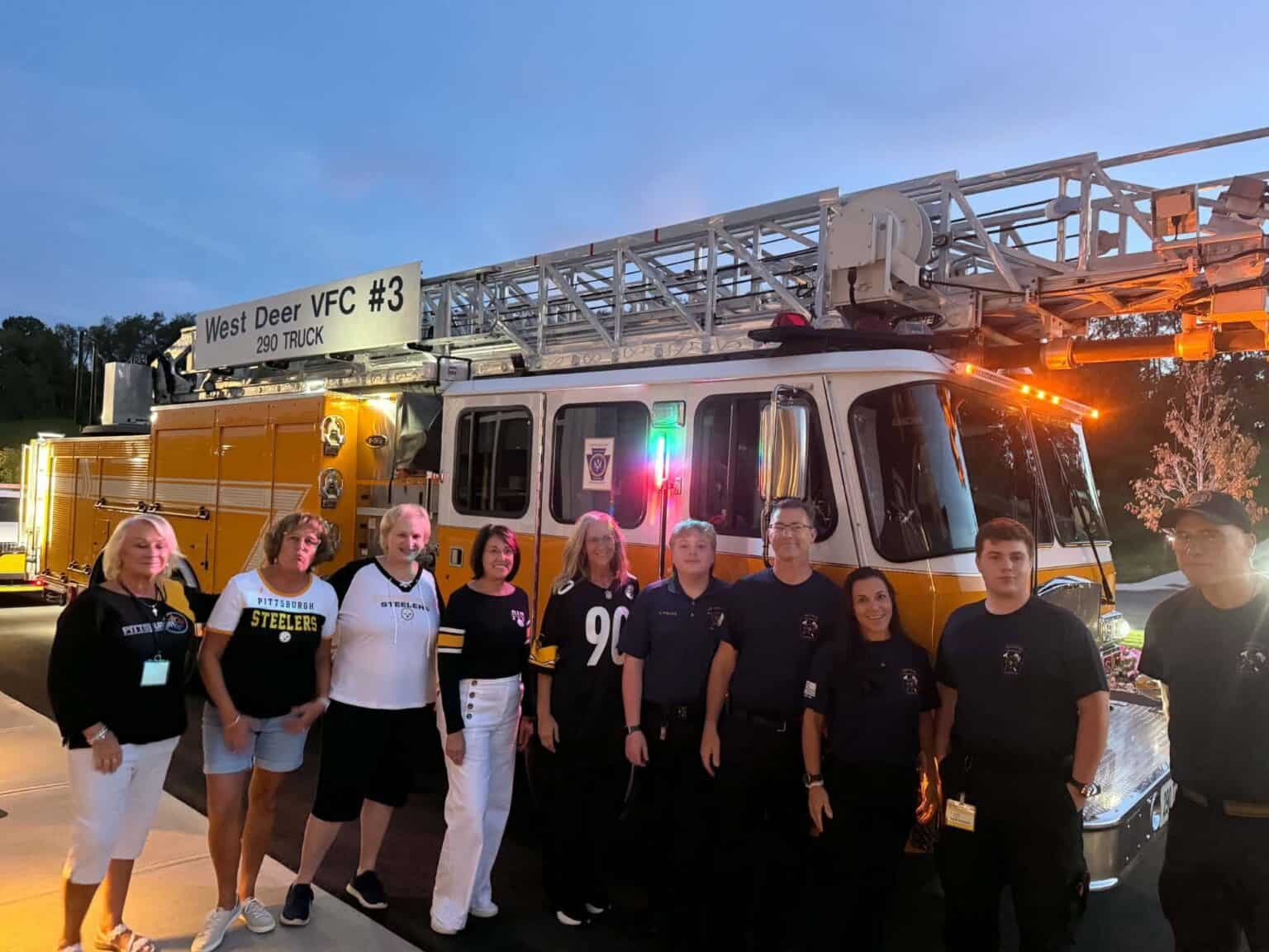A group of people standing in front of a yellow West Deer VFC #3 ladder truck.