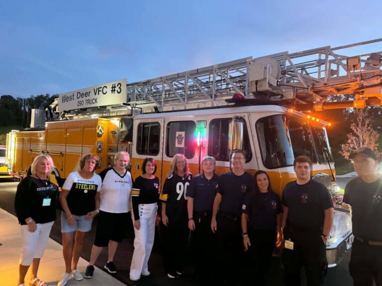 A group of people standing in front of a yellow West Deer VFC #3 ladder truck.