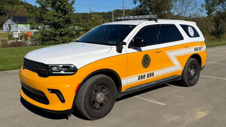 White and yellow emergency response SUV labeled “290 QRS” and “DIAL 911” parked in a lot.
